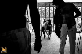 The groom gets dressed with his best men during wedding preparations at Domaine de Patras, France, captured in black and white